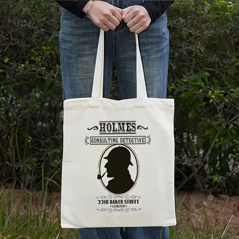 Bolsa de tela sostenida por una persona, con diseño vintage que incluye la silueta de un detective con pipa y la inscripción Holmes Consulting Detective